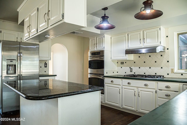 kitchen featuring stainless steel appliances, white cabinets, a center island, and decorative backsplash