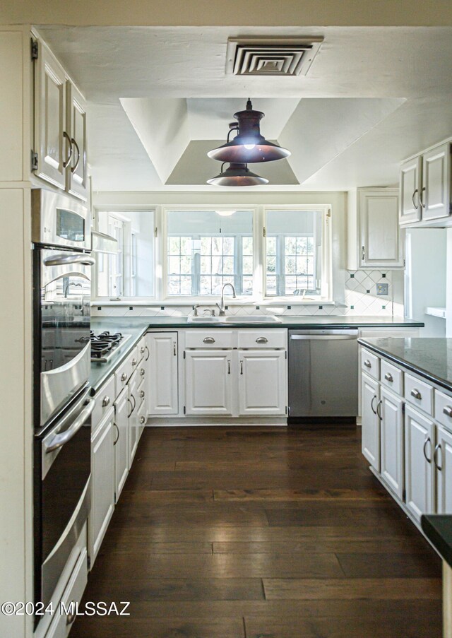 kitchen with decorative backsplash, sink, stainless steel appliances, dark hardwood / wood-style floors, and white cabinetry