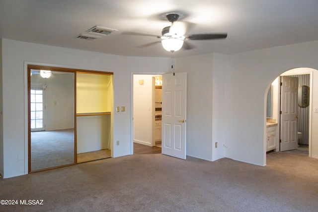 unfurnished bedroom featuring carpet floors, ensuite bathroom, and ceiling fan