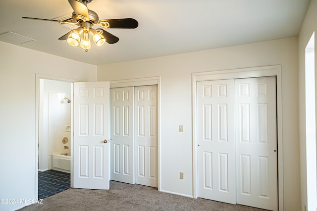 unfurnished bedroom featuring two closets, carpet flooring, and ceiling fan