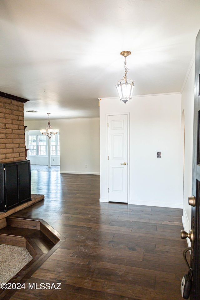 unfurnished living room featuring a brick fireplace, dark hardwood / wood-style floors, and ornamental molding