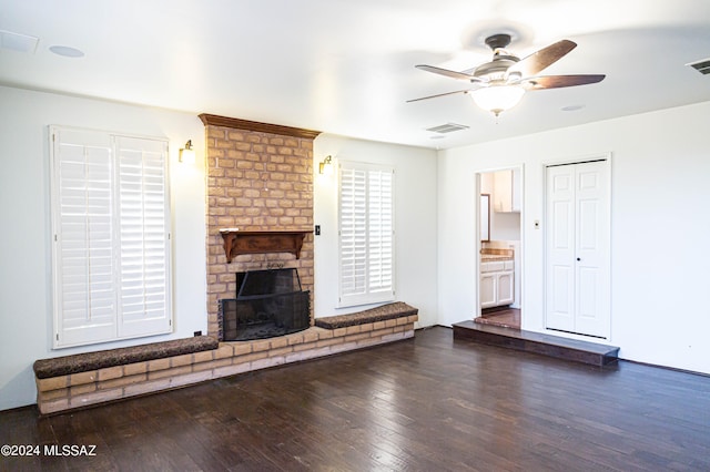 unfurnished living room featuring a brick fireplace, ceiling fan, and dark hardwood / wood-style floors