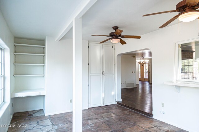 interior space featuring ceiling fan with notable chandelier and dark hardwood / wood-style flooring