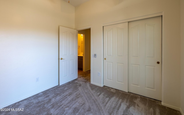 unfurnished bedroom with dark carpet and a closet