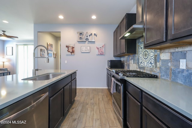 kitchen featuring stainless steel appliances, decorative backsplash, sink, light hardwood / wood-style floors, and wall chimney exhaust hood