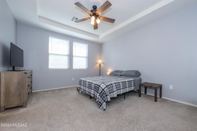 carpeted bedroom featuring ceiling fan and a tray ceiling