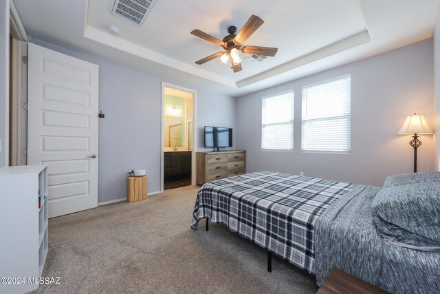 bedroom featuring ensuite bathroom, ceiling fan, and a tray ceiling