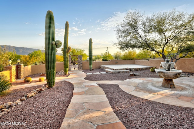 yard at dusk featuring a mountain view and a patio