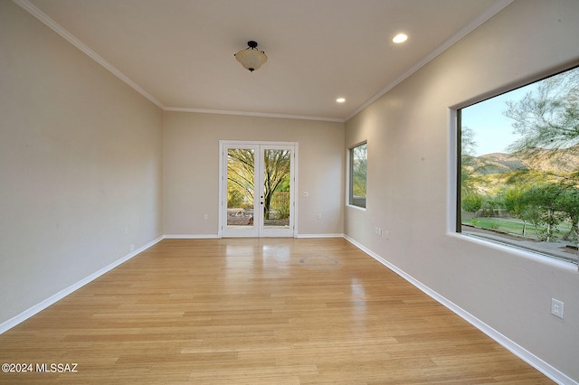 empty room with french doors, light wood-type flooring, and crown molding