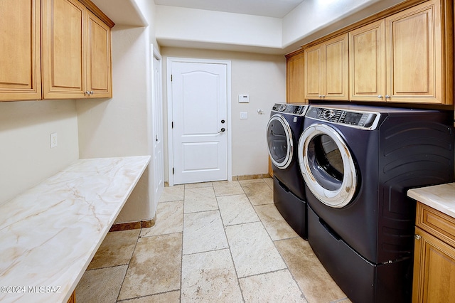 clothes washing area with cabinets and washing machine and dryer