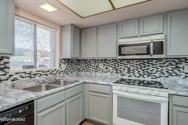 kitchen featuring white gas range oven, gray cabinets, tasteful backsplash, sink, and dishwasher