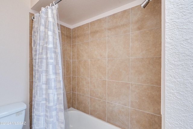 bathroom with toilet, shower / bath combo, and a textured ceiling