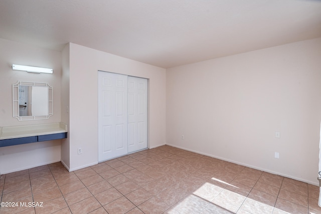 unfurnished bedroom with light tile patterned flooring and a closet