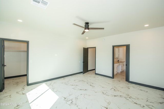 unfurnished bedroom featuring ceiling fan, a closet, ensuite bath, and a walk in closet