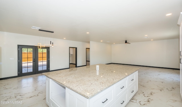 kitchen featuring ceiling fan, hanging light fixtures, french doors, white cabinetry, and light stone countertops