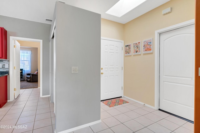 foyer entrance with light tile patterned floors, baseboards, visible vents, and a skylight