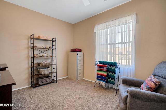 living area featuring ceiling fan, carpet floors, a healthy amount of sunlight, and baseboards