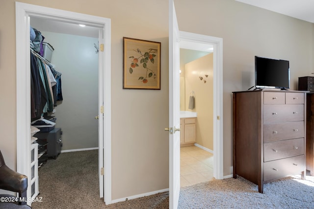 bedroom with ensuite bathroom, baseboards, and carpet floors
