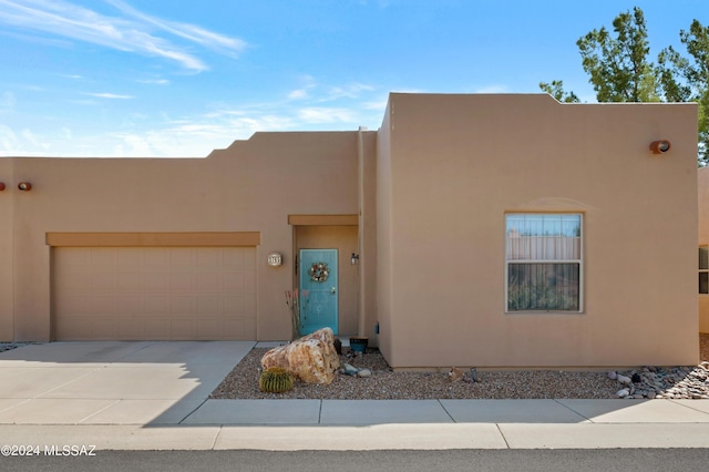 adobe home featuring an attached garage, concrete driveway, and stucco siding