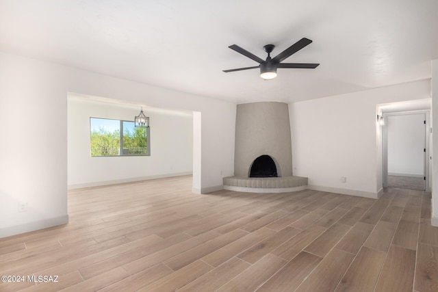 unfurnished living room featuring ceiling fan, light wood-type flooring, and a large fireplace