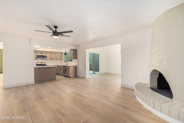 unfurnished living room with ceiling fan, sink, and light hardwood / wood-style flooring