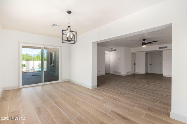 unfurnished room featuring hardwood / wood-style flooring and ceiling fan with notable chandelier