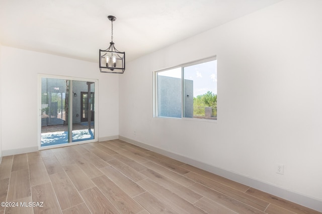 empty room featuring an inviting chandelier and light hardwood / wood-style floors