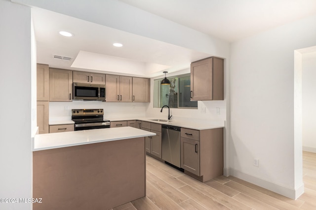 kitchen featuring stainless steel appliances, decorative light fixtures, sink, and light wood-type flooring