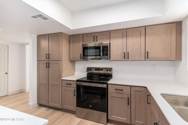 kitchen featuring stainless steel appliances, sink, and light hardwood / wood-style flooring