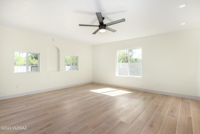 spare room featuring light wood-type flooring, a healthy amount of sunlight, and ceiling fan