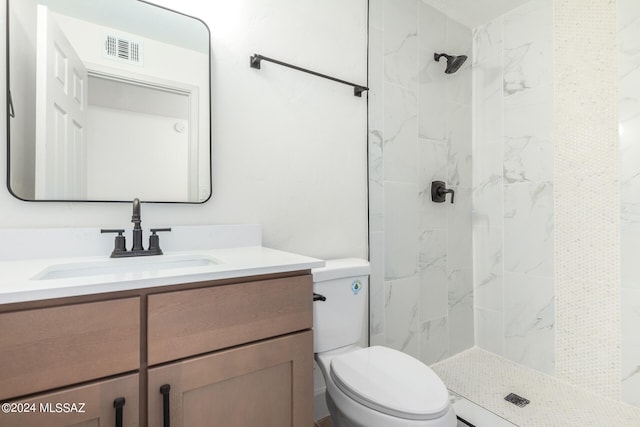 bathroom featuring tiled shower, vanity, and toilet