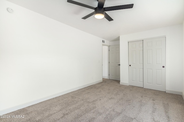 unfurnished bedroom with ceiling fan, light colored carpet, and a closet