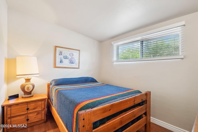 bedroom with lofted ceiling and dark hardwood / wood-style floors