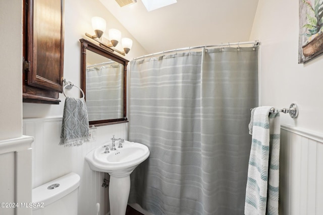 bathroom featuring toilet and vaulted ceiling with skylight