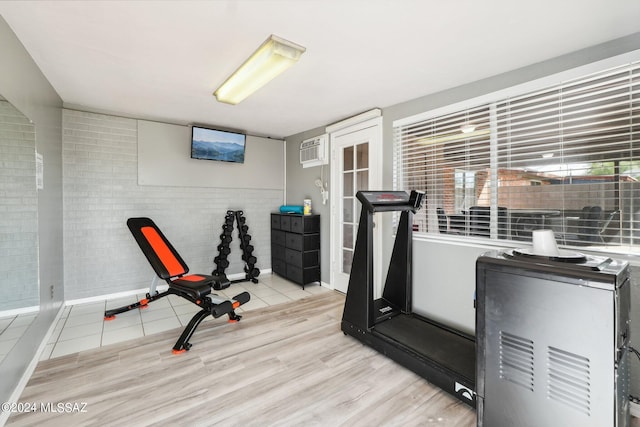 exercise area with a wall mounted air conditioner and light tile patterned floors