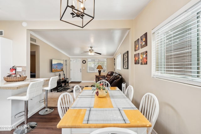 dining space with wood-type flooring, lofted ceiling, ceiling fan with notable chandelier, and ornamental molding