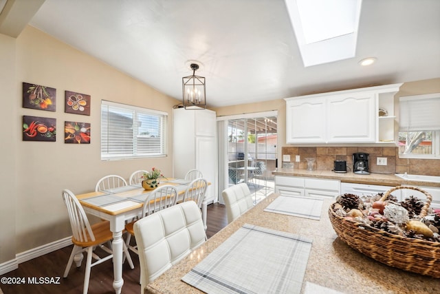 kitchen with backsplash, dark hardwood / wood-style flooring, hanging light fixtures, white cabinets, and light stone counters