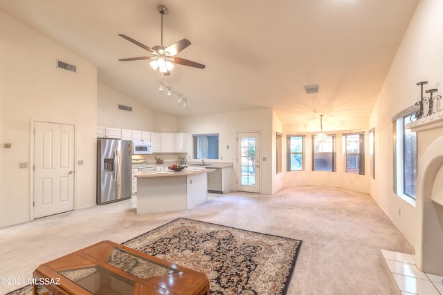 carpeted living room with ceiling fan, plenty of natural light, rail lighting, and high vaulted ceiling