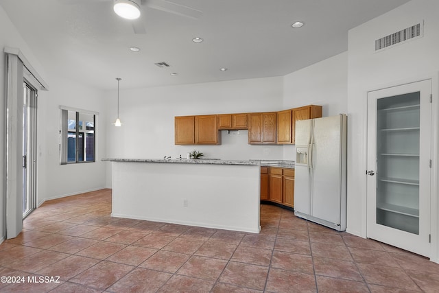 kitchen with tile patterned floors, ceiling fan, white refrigerator with ice dispenser, a center island, and hanging light fixtures