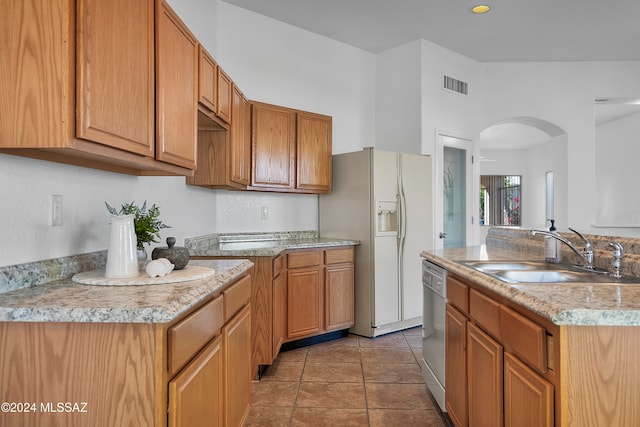 kitchen with dishwasher, white refrigerator with ice dispenser, sink, a kitchen island, and light tile patterned flooring