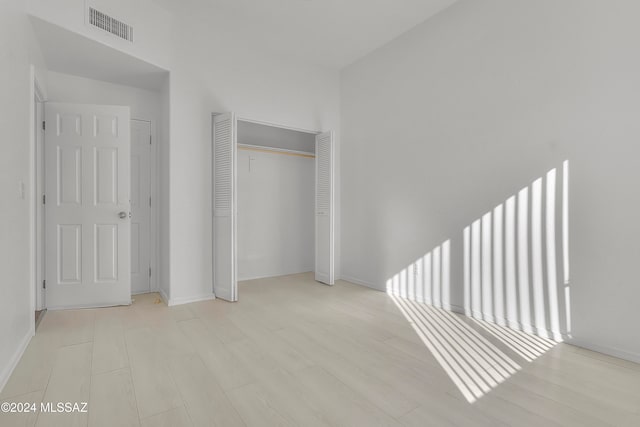 unfurnished bedroom featuring light wood-type flooring and a closet