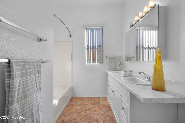 bathroom with tile patterned flooring, vanity, washtub / shower combination, and a healthy amount of sunlight