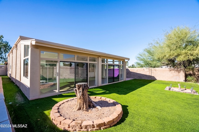 rear view of property featuring a sunroom and a yard