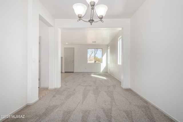 unfurnished room with light carpet, a chandelier, and baseboards