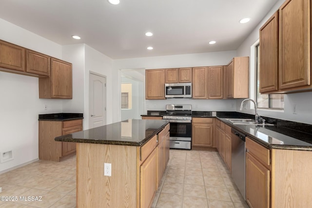 kitchen featuring a center island, light tile patterned floors, stainless steel appliances, a sink, and dark stone counters