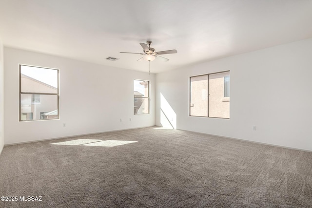 carpeted spare room with visible vents and a ceiling fan