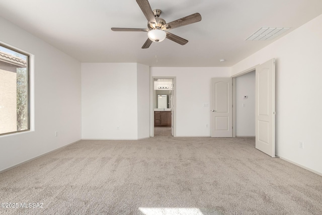 unfurnished bedroom with a ceiling fan, visible vents, connected bathroom, and light colored carpet