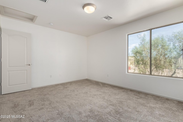 empty room with carpet floors, attic access, visible vents, and a wealth of natural light