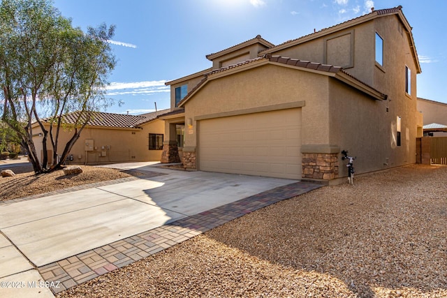 mediterranean / spanish-style house with stone siding, driveway, an attached garage, and stucco siding