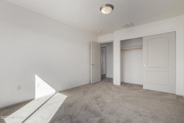 unfurnished bedroom featuring a closet, visible vents, light carpet, and baseboards